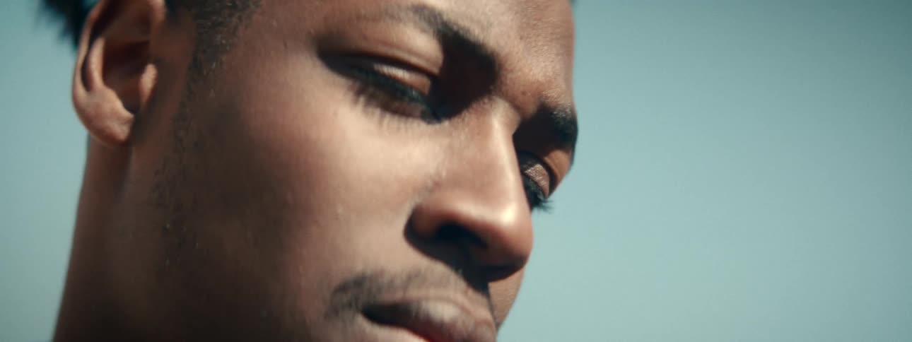 An extreme close-up of a pensive young Black man's eyes as he looks up towards the sky in deep thought