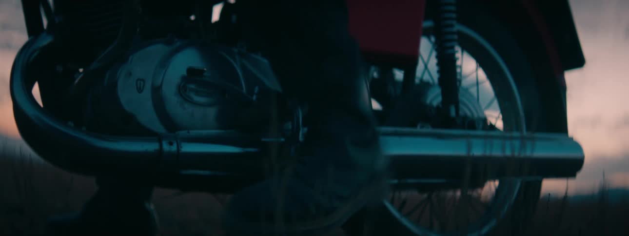 Close-up of a biker's boot using the kick-start to start a vintage motorcycle at twilight