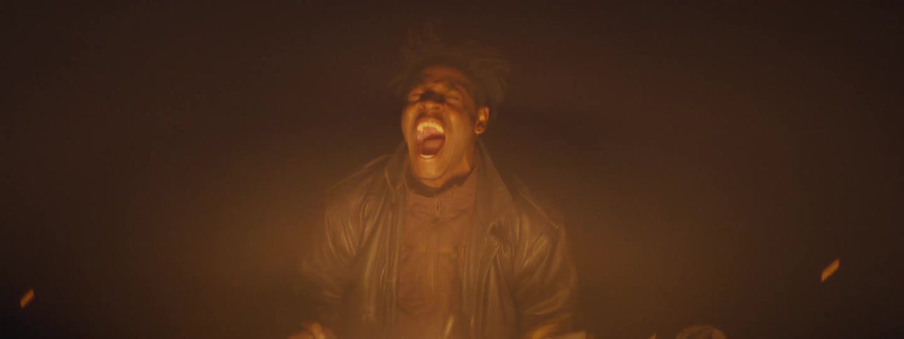 An anguished man screams in pain while sitting by a fire in the darkness