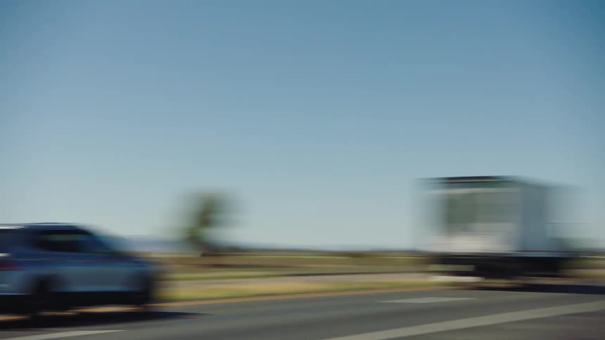 A fast pan reveals the 'Welcome to California' sign alongside a busy desert highway