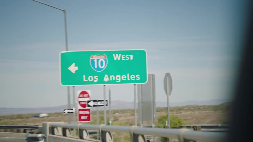 A point-of-view shot from a car driving past the Interstate 10 West Los Angeles highway sign in the desert