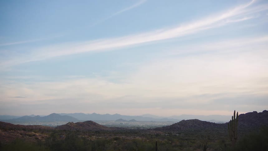 A serene, wide view of the desert valley and distant mountains under a calm blue sky in Arizona