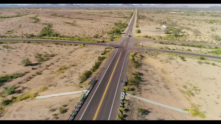 Aerial shot rises from an Interstate 10 West highway sign pointing to Los Angeles to reveal the vast, empty desert landscape