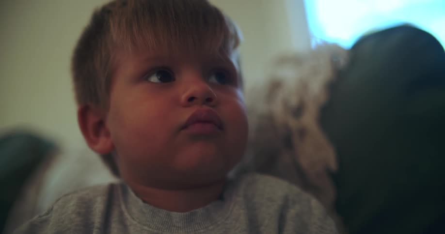 An adorable toddler is mesmerized and completely focused while watching something off-screen