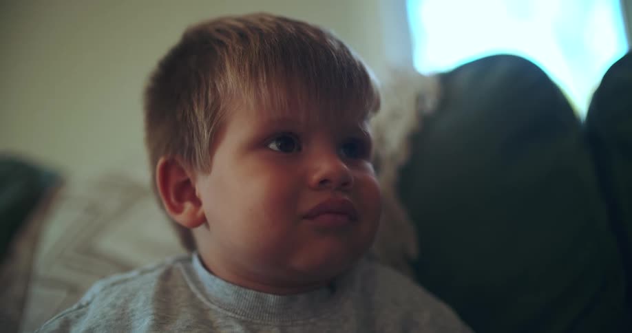 A close-up shot of a mesmerized little boy's face, staring intently while watching something off-screen