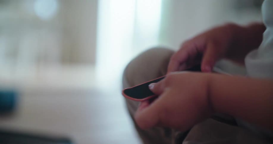 Close up slow motion shot of a child's hands playing with a toy fingerboard on a ramp indoors