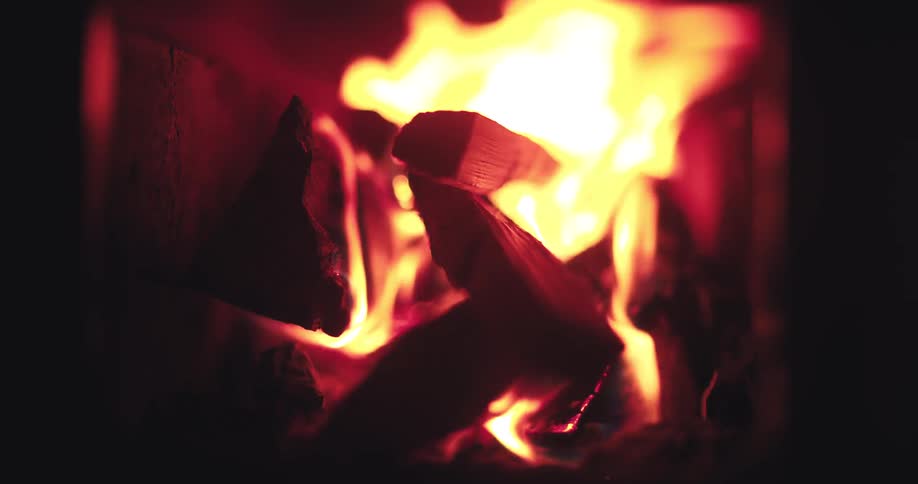 Close-up slow-motion shot of firewood burning inside a cozy fireplace