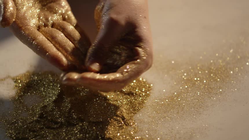 Gold glitter is all on the table, and a person is rubbing it into their hands