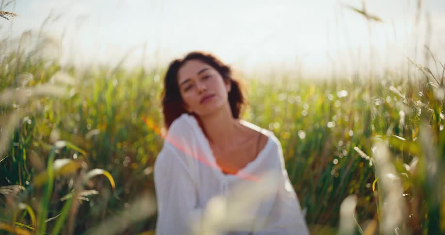 A beautiful woman finds peace and tranquility while meditating in a sun-drenched field of tall grass