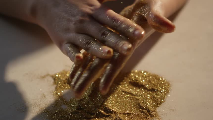 Gold glitter is being rubbed on the hands