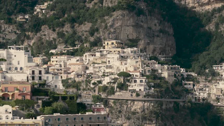 A slow zoom out reveals the picturesque town of Positano, with its charming white buildings nestled into the cliffs of the Amalfi Coast, Italy