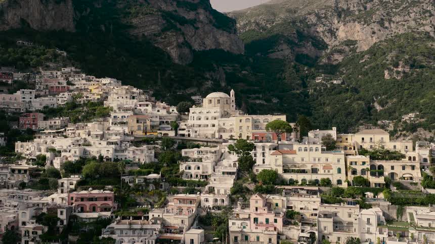 A slow aerial pullback reveals the stunning and picturesque town of Positano, built into the mountainside of Italy's famous Amalfi Coast