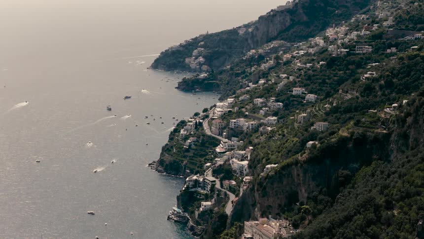 A stunning time-lapse from a high vantage point captures boats cruising along the scenic Amalfi Coast with its cliffside villages