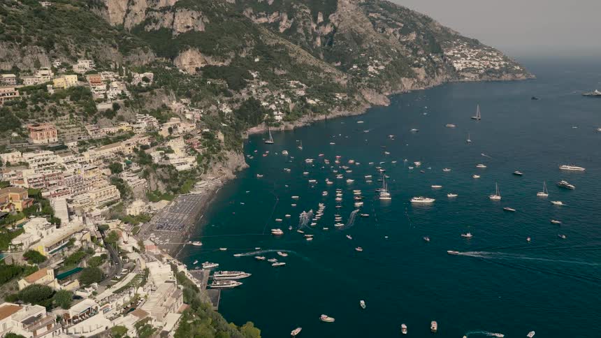 Stunning aerial view of the iconic Positano on the Amalfi Coast, with countless boats dotting the turquoise bay on a sunny summer day