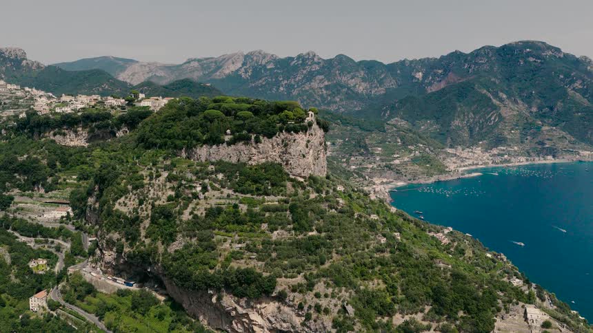 A breathtaking panoramic view of the lush, mountainous Amalfi Coast in Italy, with villages nestled into the cliffs above the sea