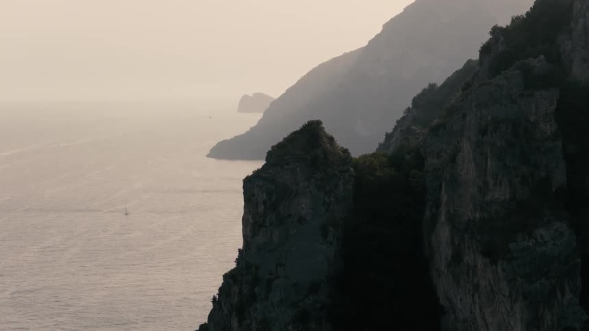 The majestic, hazy coastline and its dramatic cliffs are slowly revealed at sunrise over the ocean