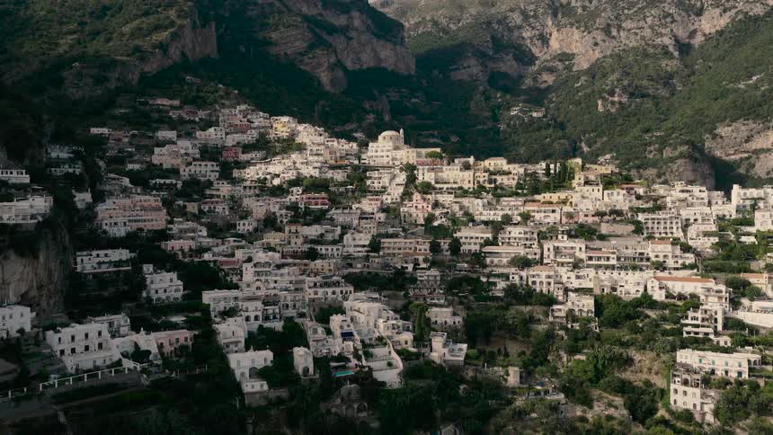 A slow aerial push-in shot reveals the iconic cliffside village of Positano on the Amalfi Coast, Italy
