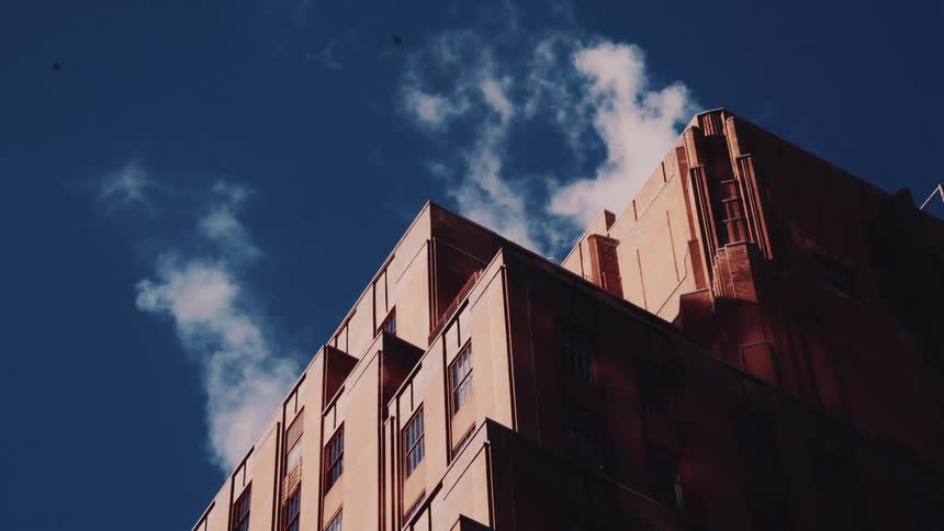 Cinemagraph of steam wafting from the top of a sunlit industrial building into a clear blue sky