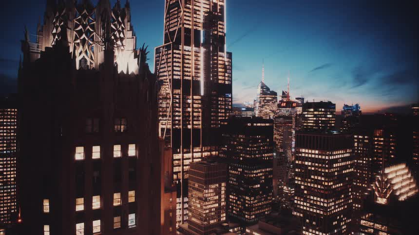 Towering skyscrapers and iconic buildings illuminate the urban skyline against a deep blue twilight sky