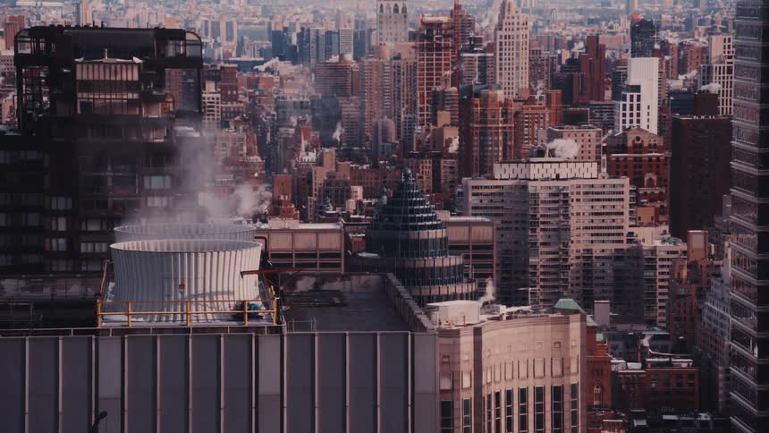 Steam rises from the rooftops of a sprawling urban cityscape on a cool day in New York City