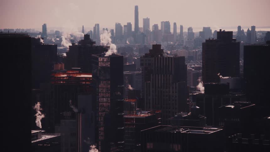 A gritty, cinematic wide shot shows steam rising from the rooftops of a sprawling urban cityscape