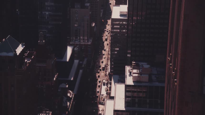 A slow tilt up from a shadowed city street reveals the vast, sunlit skyline of a metropolis
