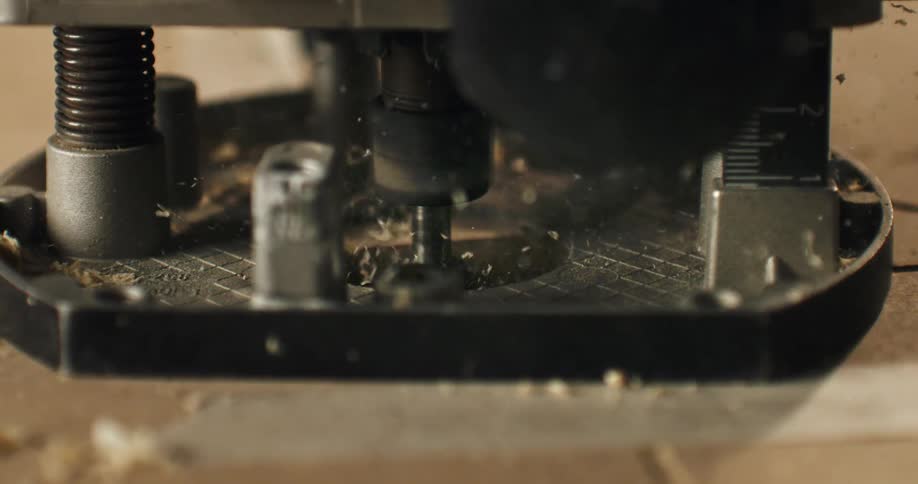 Slow-motion close-up of a powerful router bit cutting a groove in wood, with sawdust flying