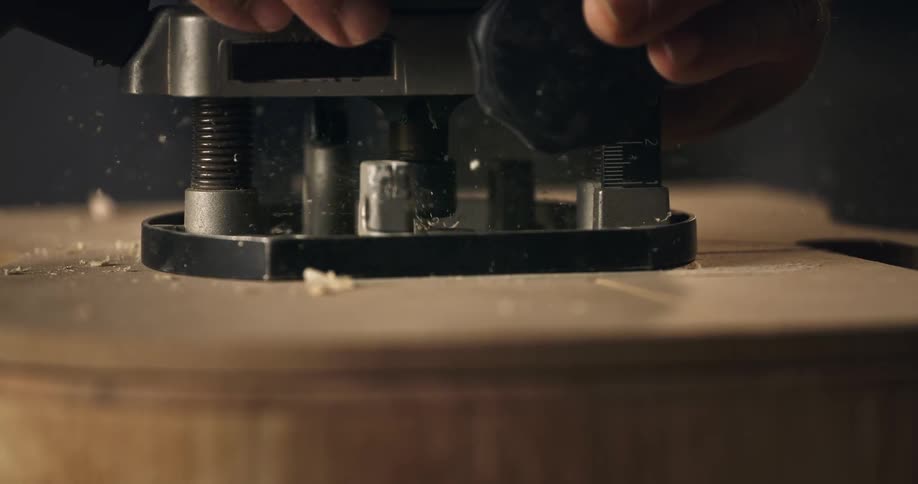 A detailed slow motion view of a router bit carving into wood, creating a spray of fine sawdust