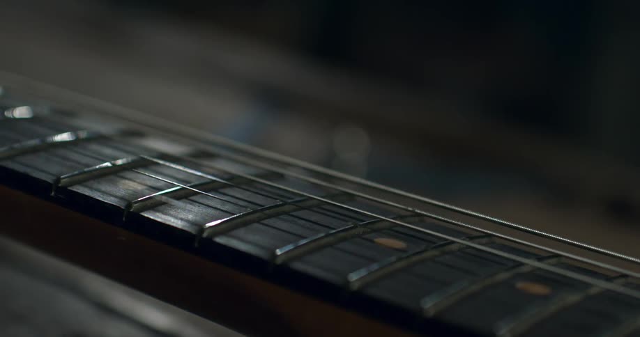 A close-up shot of an electric guitar string vibrating in slow motion along the fretboard