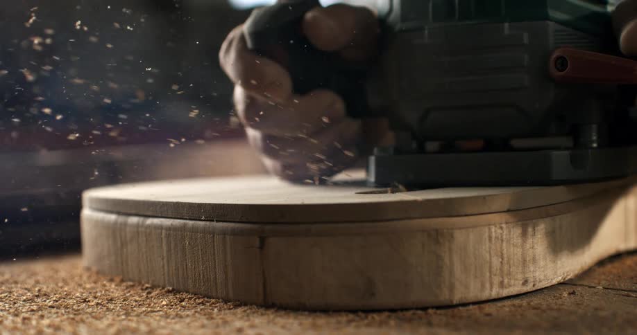 Close up slow motion cinemagraph of a jigsaw cutting through a piece of wood as sawdust flies