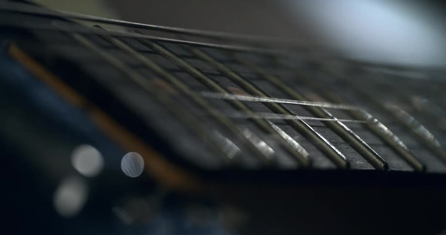 A moody macro shot shows a single guitar string vibrating in slow motion over the dark fretboard