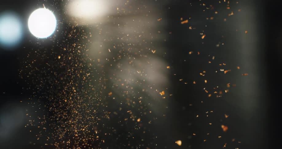 A mesmerizing slow-motion cascade of golden dust particles floating in a dark, atmospheric space