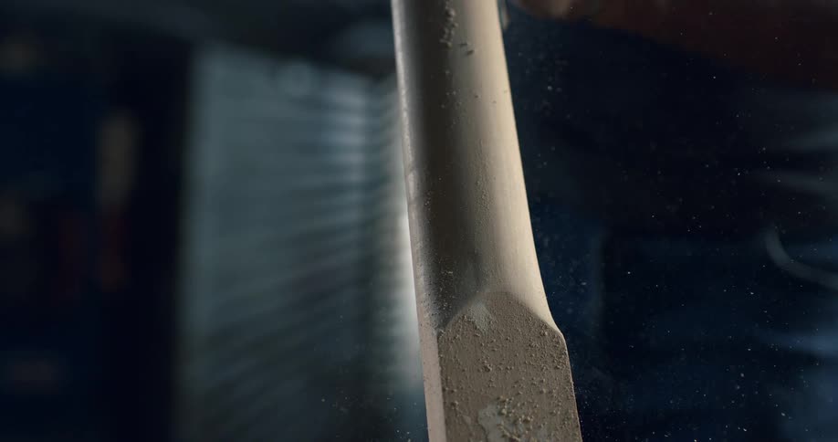 Slow motion close-up of a craftsman's hands carefully sanding a wooden cricket bat, with sawdust flying through the air