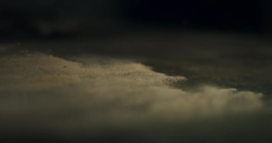 A gust of wind blows a layer of dust away in a dramatic slow motion macro shot