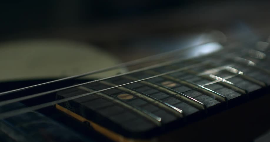 A moody macro shot shows a single electric guitar string vibrating over the frets of the fretboard