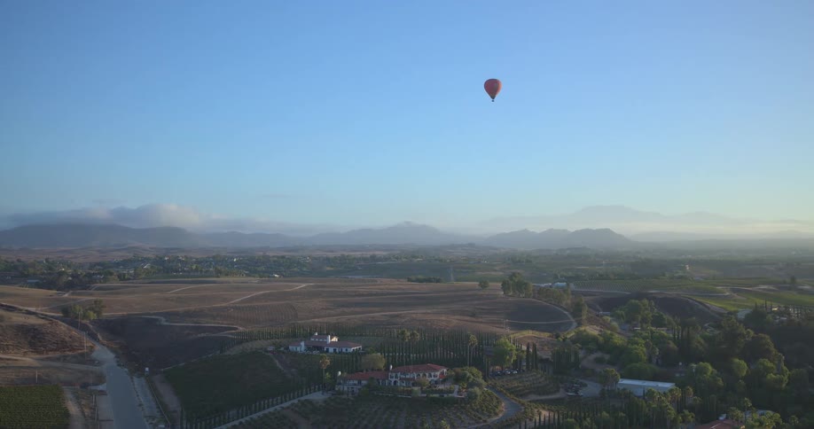 Aerial view of a hot air balloon floating over Temecula wine country during a beautiful morning sunrise