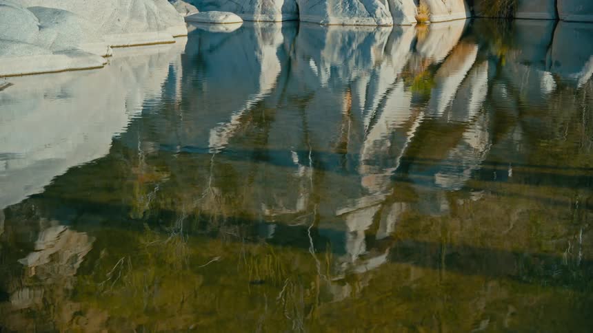 Calm creek water ripples gently, reflecting the surrounding white rock formations