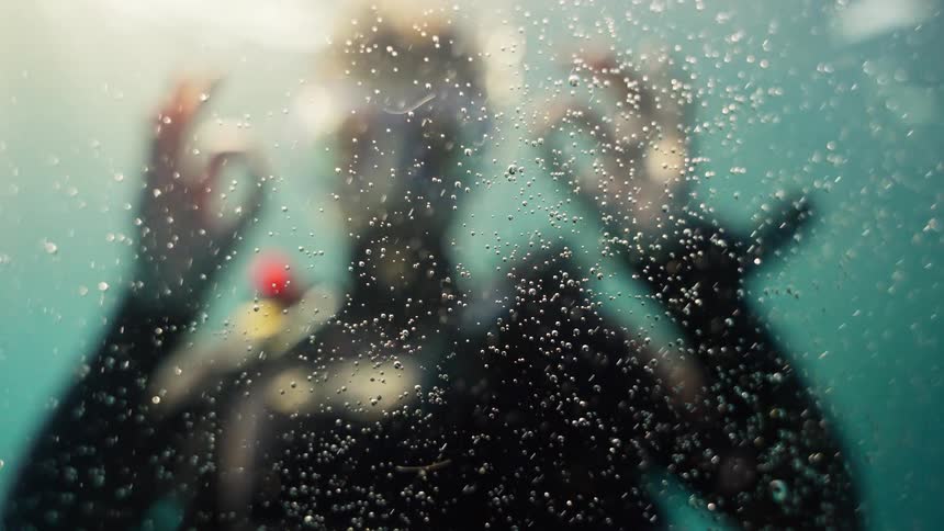 An abstract shot of air bubbles floating in the water as a scuba diver slowly descends into the depths