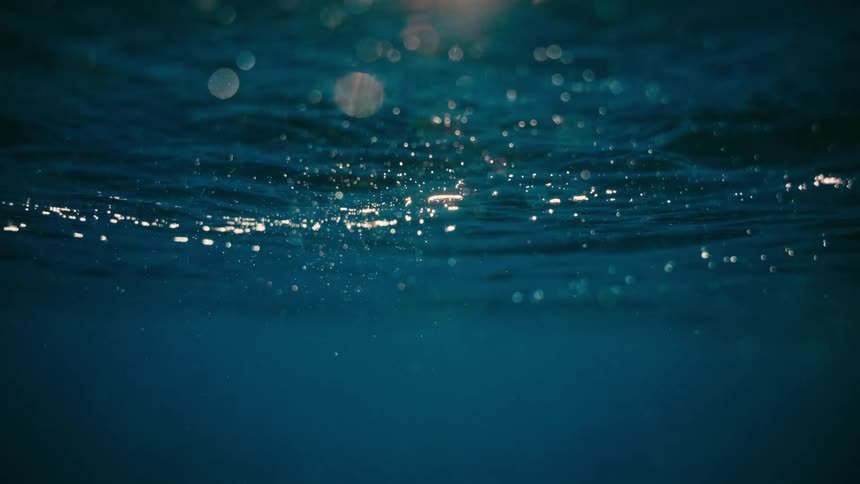 Beautiful underwater view of the ocean surface with sunlight filtering through the deep blue water
