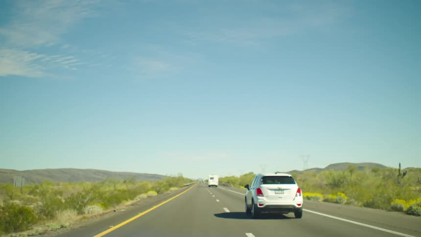 A slow-motion, point-of-view shot of driving down a desert highway on a sunny day