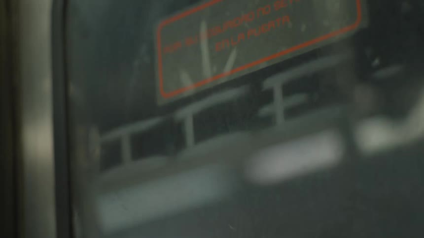 An abstract, shaky close-up of a passing platform reflected in a dirty subway car window