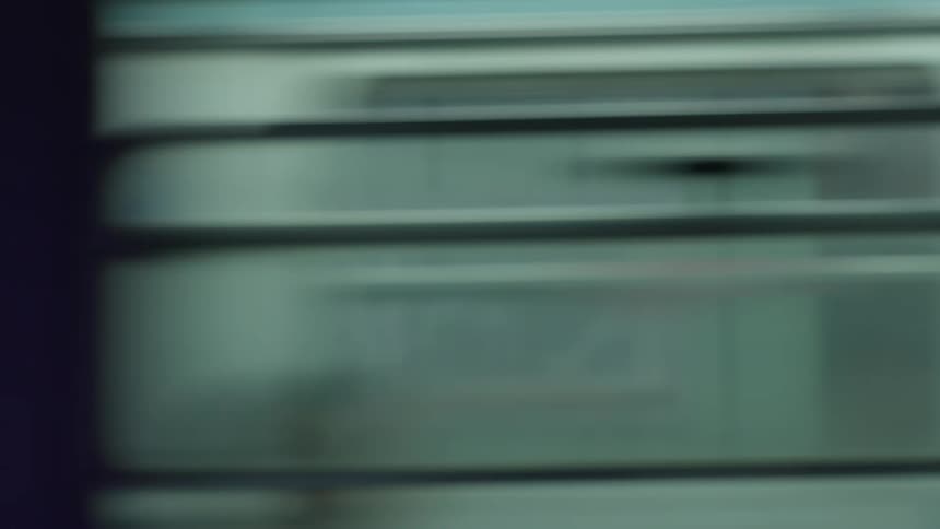 An abstract and blurry view of a passing subway train seen from a window, creating a sense of motion and urban travel