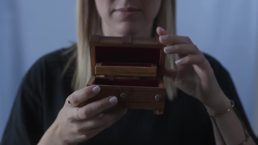 A woman closes a wood jewelry box