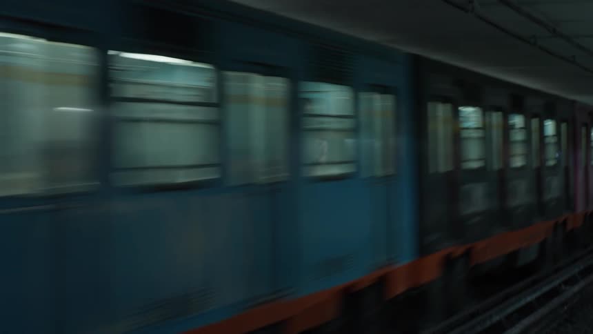 A colorful subway train speeds through a dark underground tunnel creating a dynamic motion blur effect