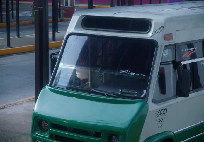Commuters waiting in line board a green and white minibus at a covered bus terminal in Mexico City