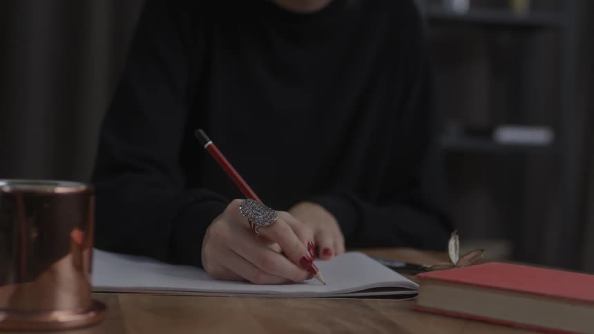 Person draws on a white book with a pencil