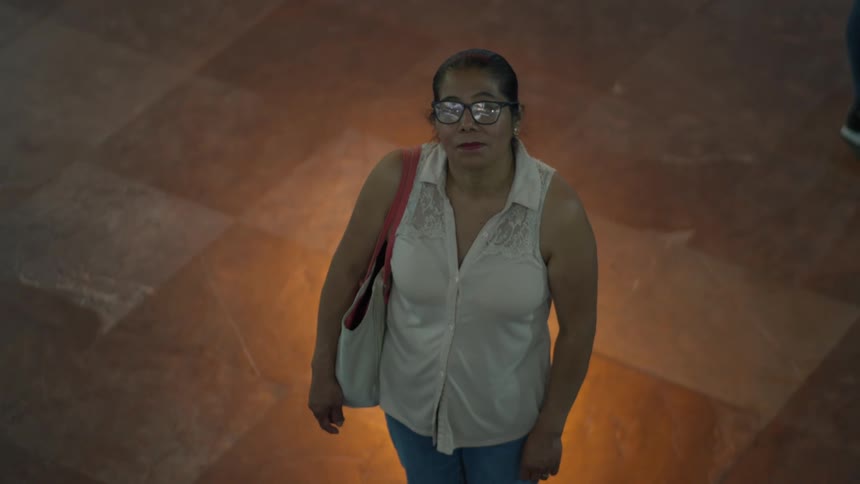 High-angle time-lapse of a woman standing still in a bustling crowd as people walk by in a blur