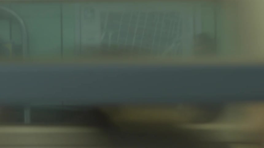A blurry, abstract point-of-view from a speeding subway train window as it passes through a station
