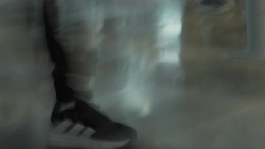A chaotic, blurry low-angle view shows the feet of people rushing past on a polished floor