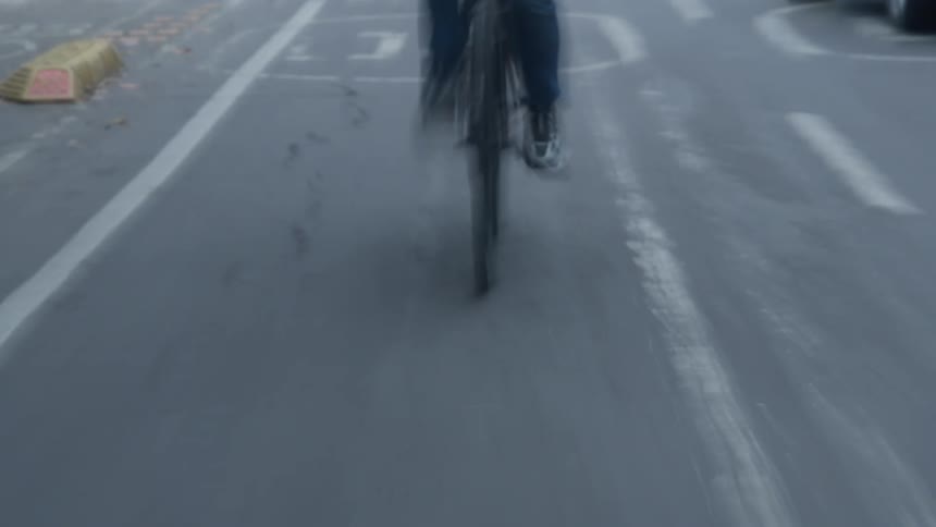Dreamy, motion-blurred POV shot follows a cyclist speeding down a dedicated city bike lane